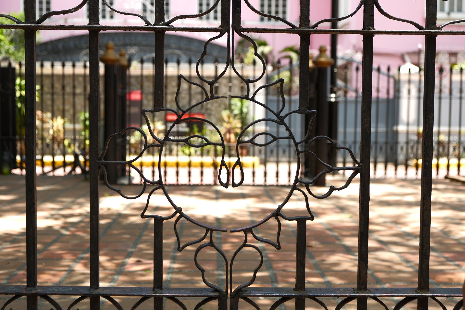 An iron gate featuring a sun design, set in a tranquil courtyard on a sunny day in Mount Pleasant, SC